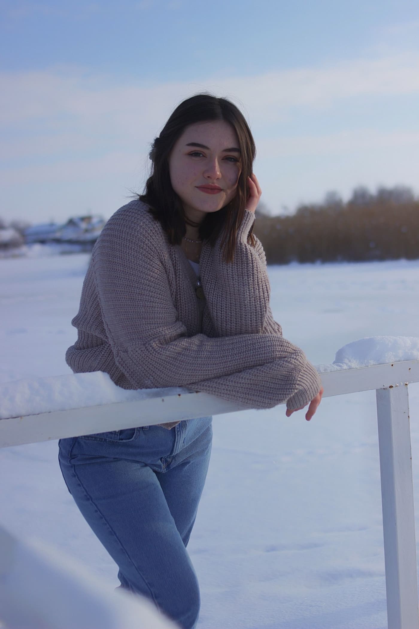 A woman in a brown knit sweater and jeans.